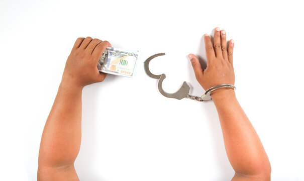 A man's hand is uncuffed and the other hand is holding a dollar bill. White background. isolated.with clipping path.corruption concept.