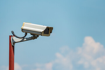 Surveillance camera security background. Camera against blue sky copy space.
