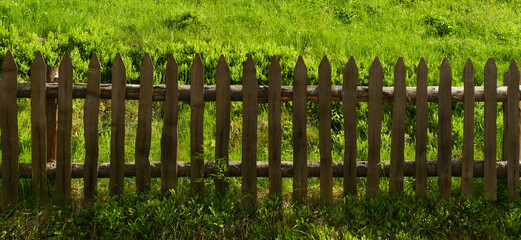 Wooden fence against the background of green grass. Old fence panoramic big size background for design and decoration.