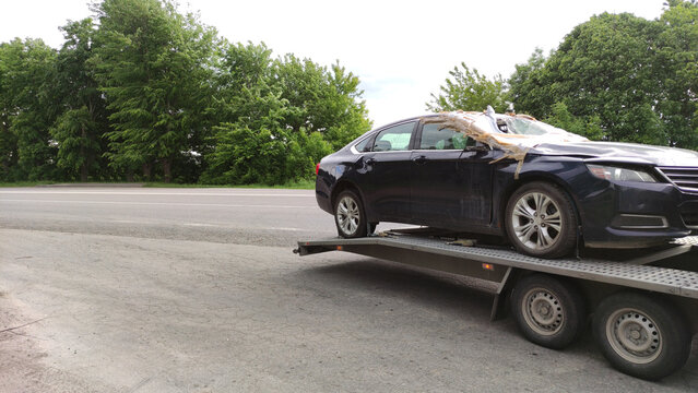 Damaged car on a tow truck. Car towing service. Broke auto concept background. Automobile insurance.