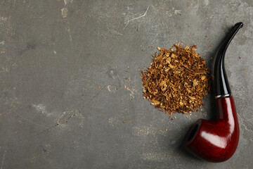 Pile of tobacco and smoking pipe on grey table, flat lay. Space for text