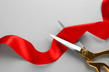 Red ribbon and scissors on light grey background, top view. Space for text - obrazy, fototapety, plakaty