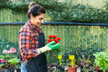 Happy woman working in plants and flowers garden shop