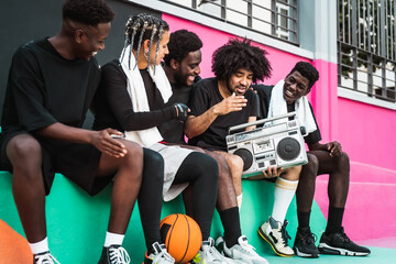 Young people having fun listening music with vintage boombox outdoor - Urban street people lifestyle