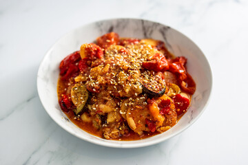 vegan roast with potatoes zucchini and tomatoes topped with sesame seeds, healthy plant-based food