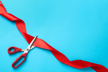 Red ribbon and scissors on light blue background, top view. Space for text - obrazy, fototapety, plakaty