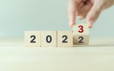 Beginning and start of the new year 2023. Preparation for happy new year ,new life, new business, plan, goals, strategy concept. Hand flips wooden cubes with  2022 to 2023 on smart background.