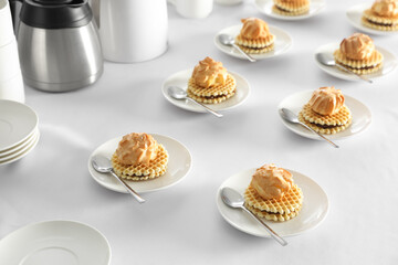 Many delicious waffles with cream served on white table for coffee break