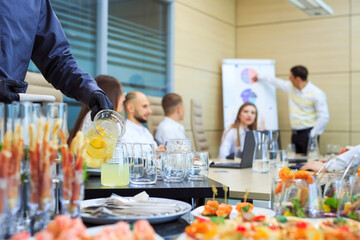 A young waiter pours drinks for catering.