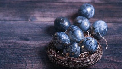 Easter card with a copy of the place for the text. Very Peri 2022 .Purple, blue eggs in a basket on a dark newspaper background. Natural dye karkade tea.