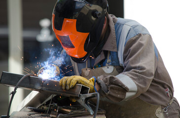blacksmith working with spot welder, worker welding with protection helmet