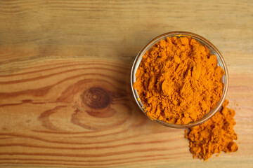 Bowl with saffron powder on wooden table, top view. Space for text
