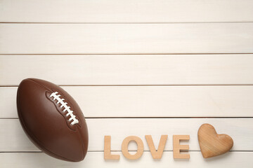American football ball, heart and word Love on white wooden background, flat lay. Space for text