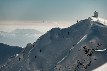 view of the mountain top covered with snow along the slope of which groups of skiers climb