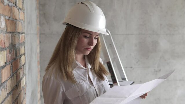 Girl engineer builder checks design drawings at a construction site. Work with architectural and design drawings.