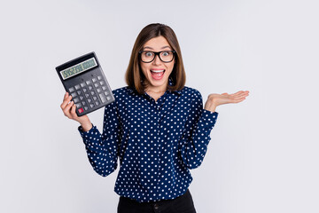 Portrait of attractive cheerful amazed girl holding calculator cash savings having fun isolated over grey pastel color background - obrazy, fototapety, plakaty