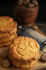 Tasty cookies, nutmeg seeds and grater on wooden board