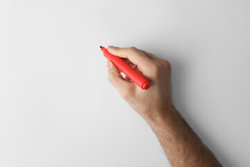 Man holding red marker on white background, top view