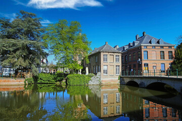 Fototapeta na wymiar Lier, Belgium - April 9. 2022: View over water town moat on medieval romantic old cityscape, ancient stone bridge, clear blue sky
