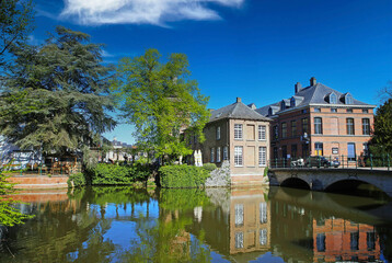 Fototapeta na wymiar Lier, Belgium - April 9. 2022: View over water moat on park, medieval old houses, ancient stone bridge, blue sky