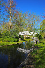 View on beautiful park in springtime with roamantic small white wood bridge, water creek and pond, blue sky - Lier, Belgium