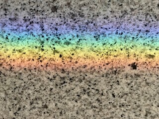 an optical rainbow colored line on gray stone background