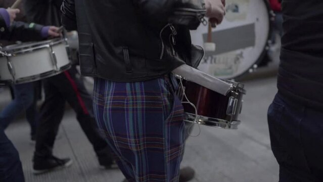A woman is playing drums while marching during a protest in the International Women's day in Quito, Ecuador. Other people on the back are also carrying and playing drums. #8M