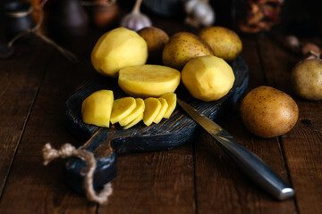 Raw fresh new potatoes on a wooden background. Sliced potatoes. Rustic style.