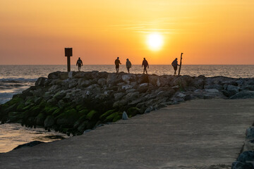 Friends watching the sunset on the breakwater of Mimizan Beach. Landes
