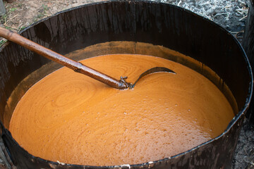 Molasses is being made from sugarcane juice in a large iron pot in a rural area, this delicious...