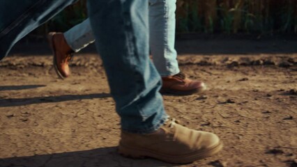 Agronomists boots walking dry ground soil together at autumn countryside closeup