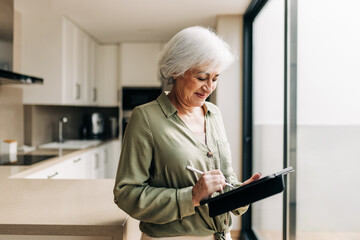 Mature woman signing on a digital tablet at home