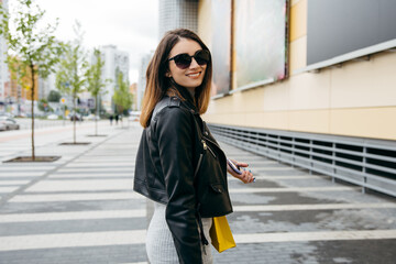 Obraz premium Skinny pretty young woman with shopping bag walking near the mall showcase