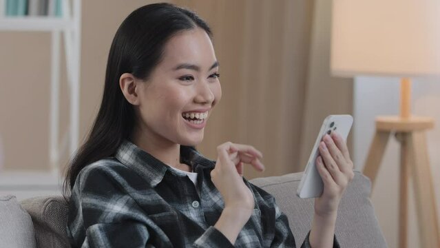 Close-up Asian girl woman with mobile phone swipe browsing online shop app choosing groceries clothes in internet service e-shopping surprised rejoices wins happy with discounts smartphone victory