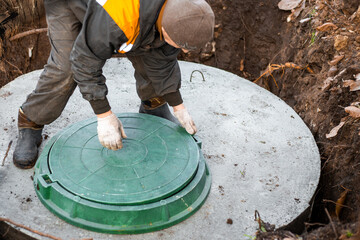 a utility worker lifts a manhole cover for sewerage maintenance and pumping out feces. Septic on a...