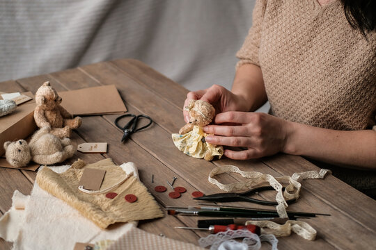 A young woman sews a teddy bear. Process of making vintage toy