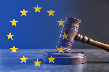 Double exposure of European union flag and judge's gavel on grey table