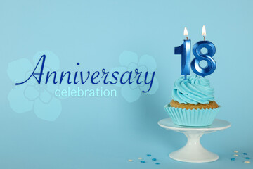 Delicious cupcake with number shaped candles on light blue background. Coming of age party - 18th birthday. Anniversary celebration