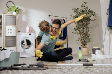 A man cleans together with child, sits on the bathroom floor, laundry room, and mops the floor with...