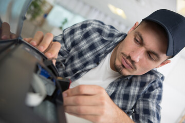 male worker changing ink cartridge on printer