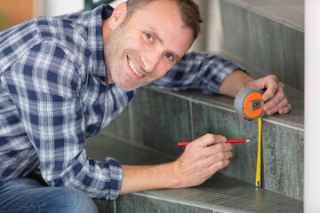 happy male worker is using tape measure