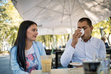 Romantic moments of young couple sitting in a cafe and drinking hot drink, outdoors.