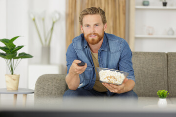 man eating popcorn on the sofa - studio shoot