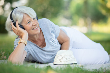 an attractive senior woman using headphones on the grass