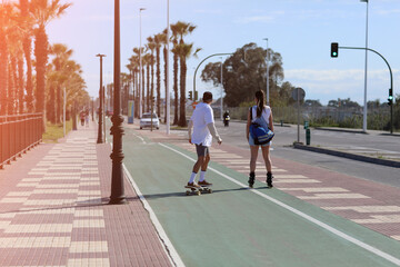 holidays vacations. a woman on roller skates and a man on a skateboard are having fun outdoors on...