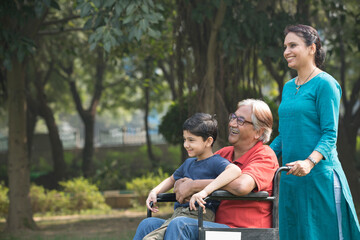 Mother and son with old man in wheelchair at park