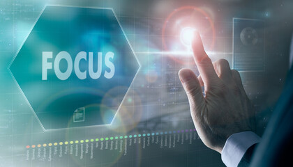 A businessman controlling a futuristic display with a Focus business concept on it.