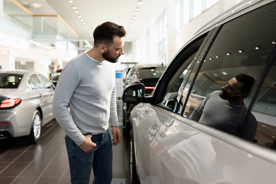 a man examines the range of cars in the showroom for a car dealership