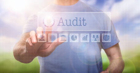 A man in a t-shirt outside selecting a Audit word concept on a computerised display