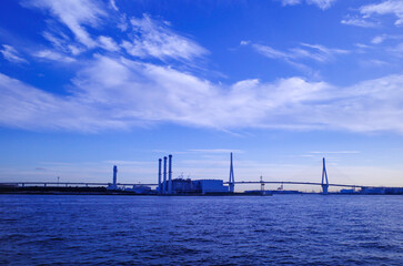 海芝公園から青空に映える海越しのベイブリッジと工場地帯